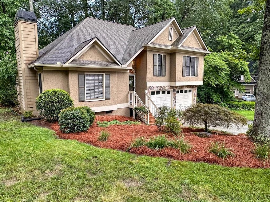 View of front of house with a chimney, stucco siding, a garage, a shingled roof, and a front lawn