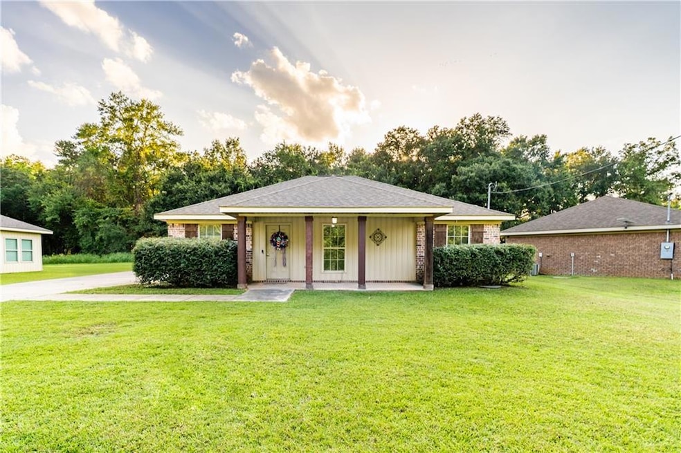 View of front of house with a front yard, brick siding, covered porch, and roof with shingles
