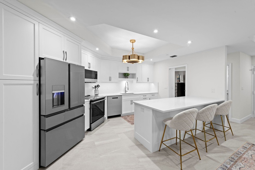 Kitchen featuring recessed lighting, appliances with stainless steel finishes, a kitchen bar, white cabinetry, and hanging light fixtures