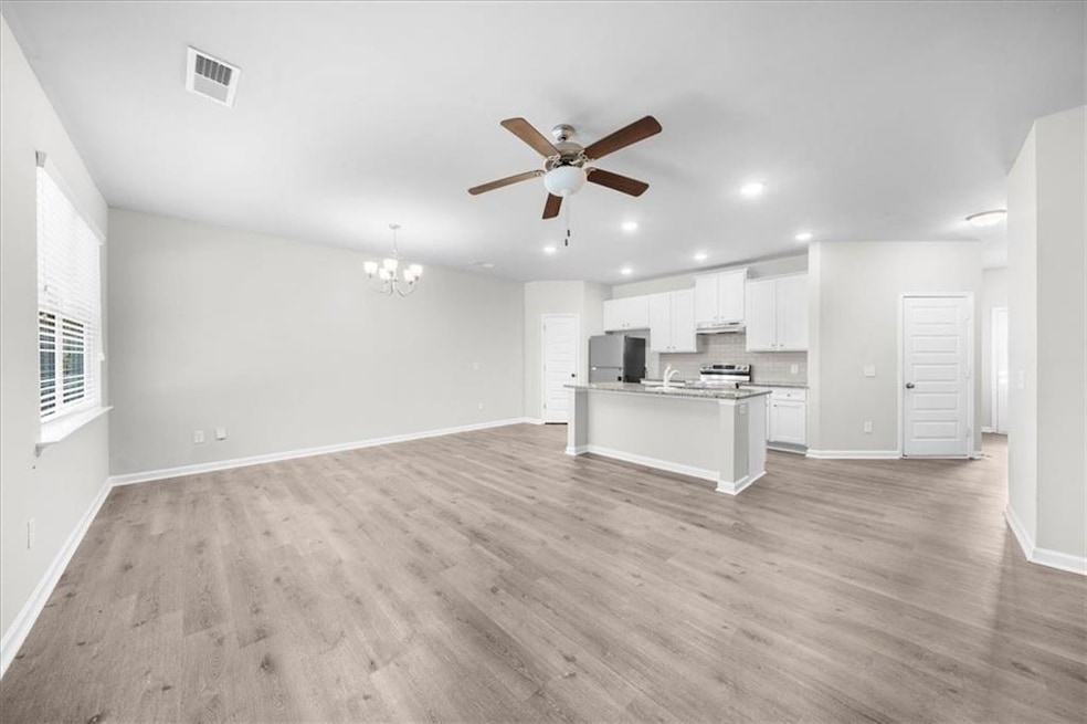 Unfurnished living room with a chandelier, ceiling fan, recessed lighting, and light wood-style floors