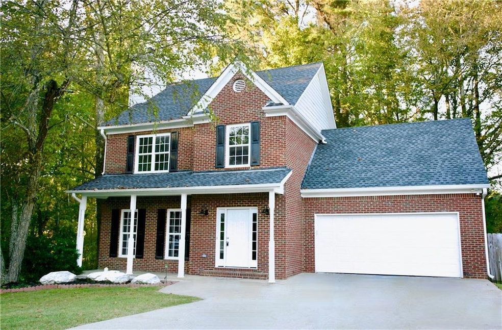 Traditional home featuring driveway, a porch, brick siding, and an attached garage