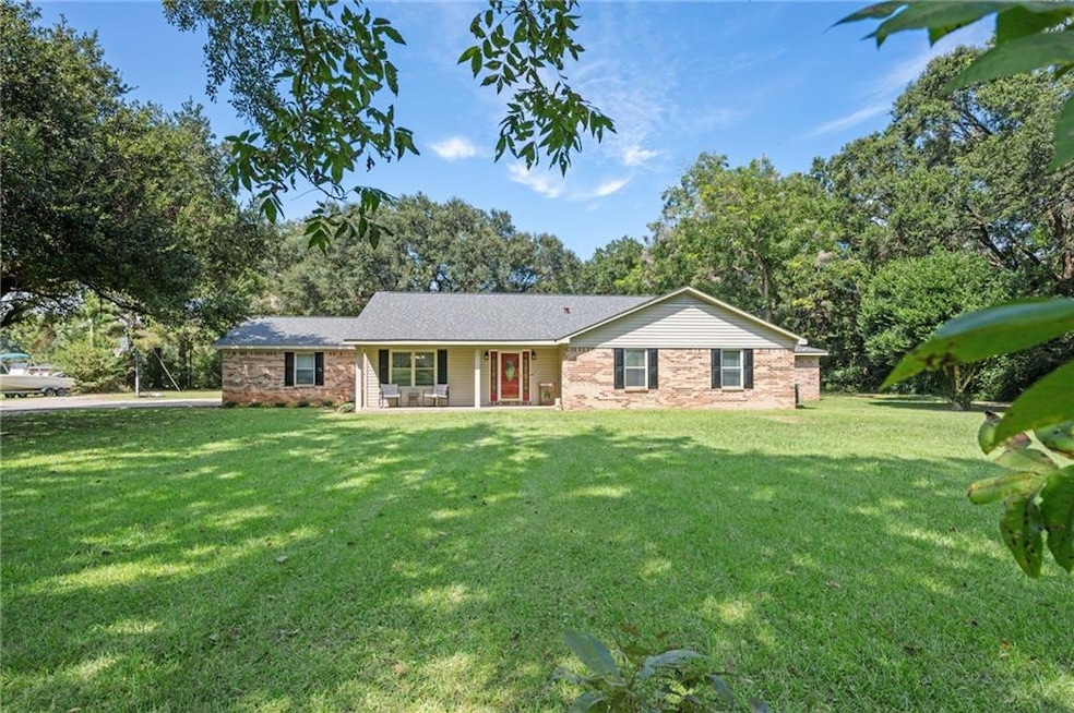 Single story home featuring a front lawn, covered porch, and brick siding