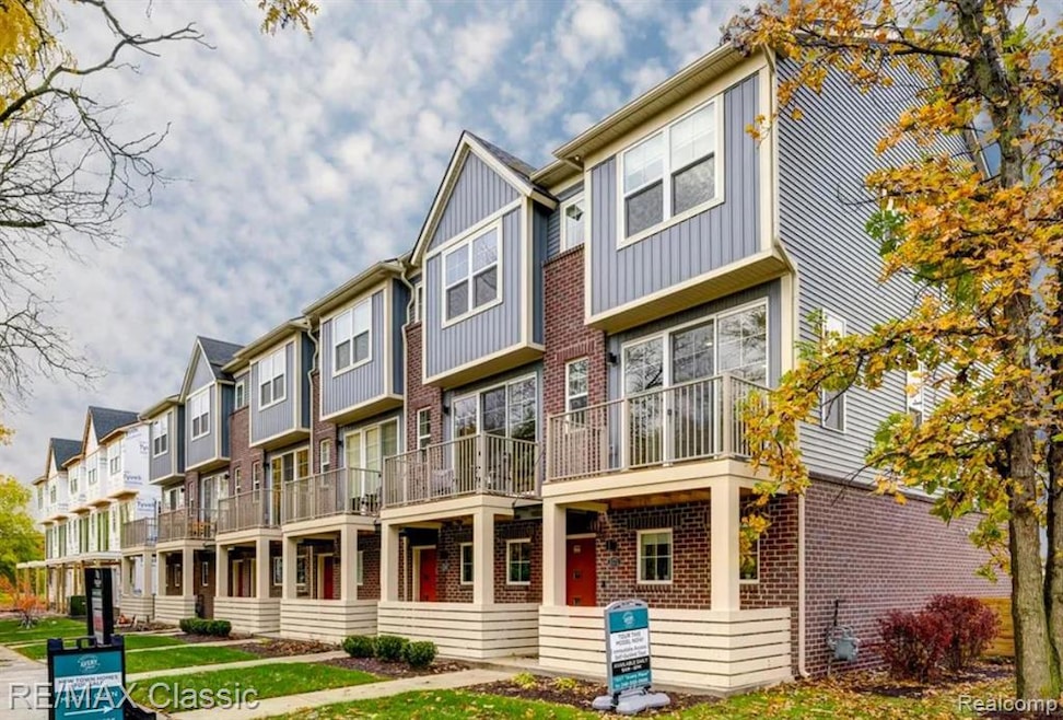 View of front of property featuring brick siding, a residential view, a balcony, and board and batten siding