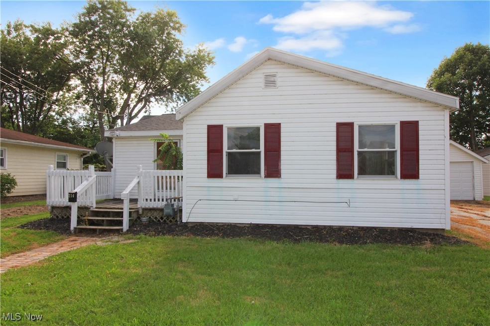 View of front of property featuring a front lawn, a deck, and a garage