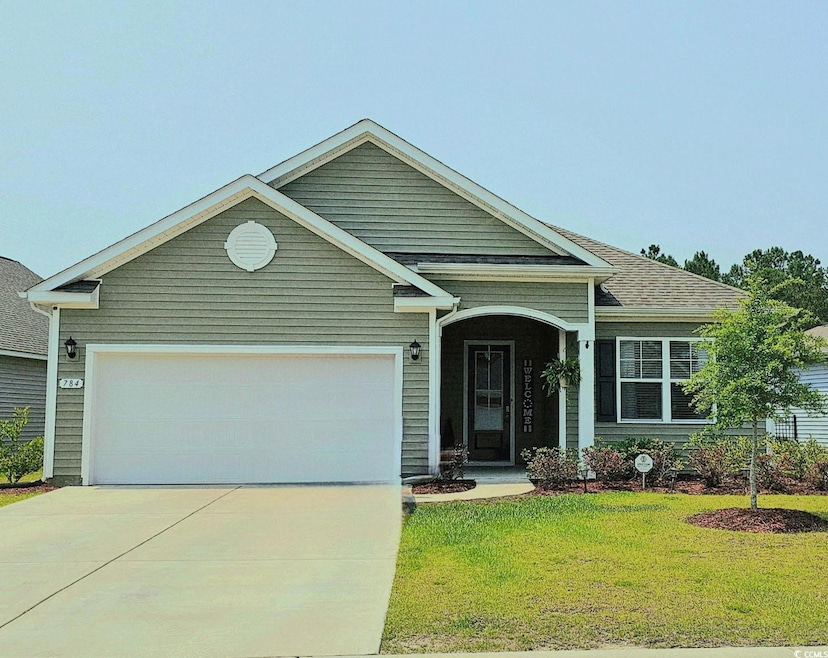 View of front of house with concrete driveway, an attached garage, and a front lawn