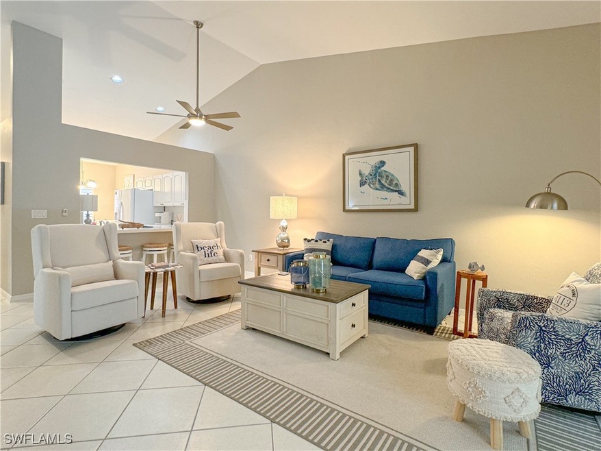 Tiled living room with ceiling fan and vaulted cei
