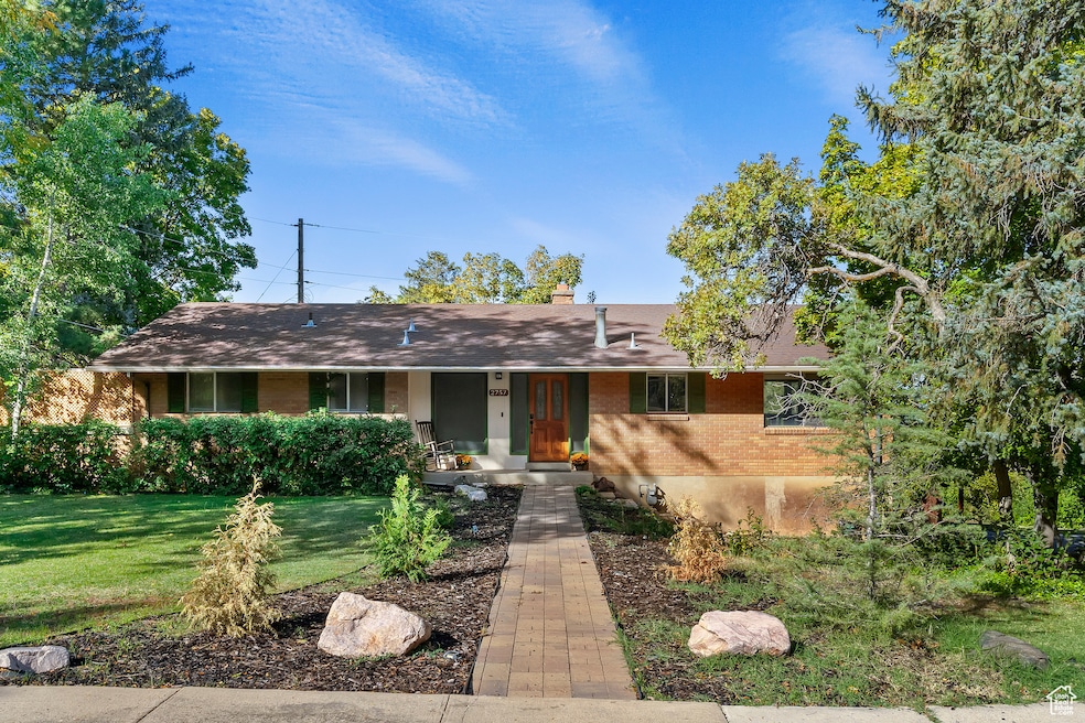 Ranch-style house with brick siding, a front yard, a chimney, and covered porch