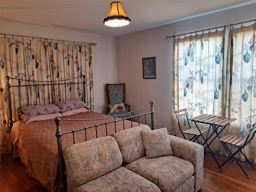 Bedroom with wood finished floors and multiple wi