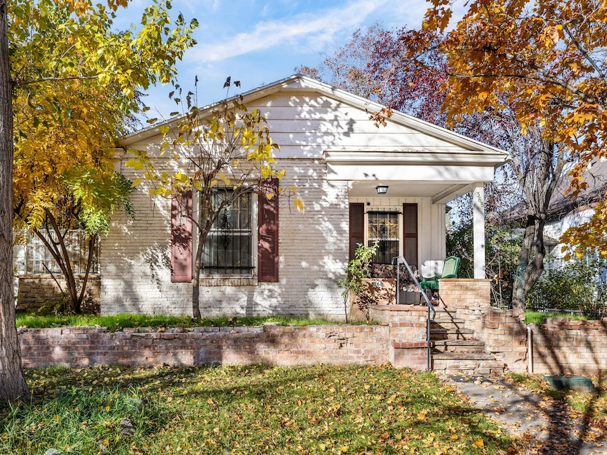 View of front of property with covered porch, brick siding, a front lawn, and stairway