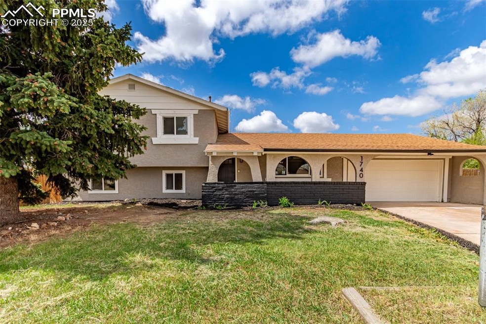 Tri-level home featuring stucco siding, an attached garage, concrete driveway, and a front yard