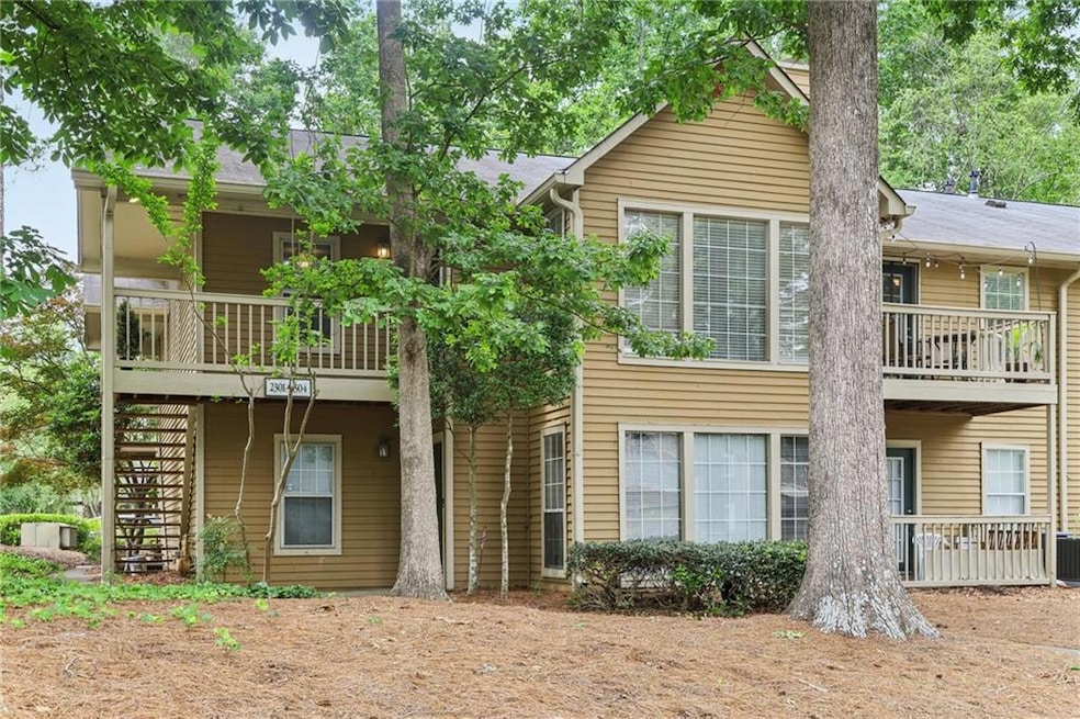 Back of property with stairs, central AC unit, and a balcony