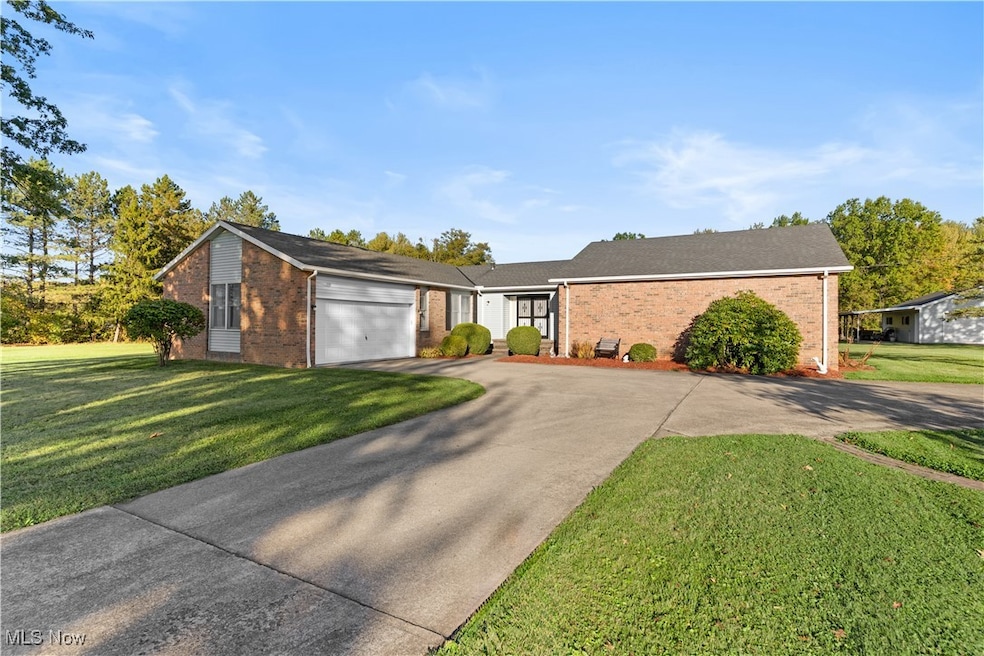 View of front of property featuring a front lawn, concrete driveway, and brick siding