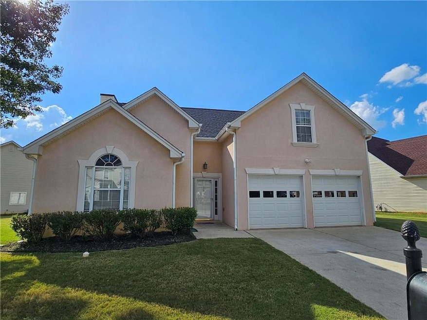 View of front facade featuring stucco siding, concrete driveway, a front lawn, and an attached garage