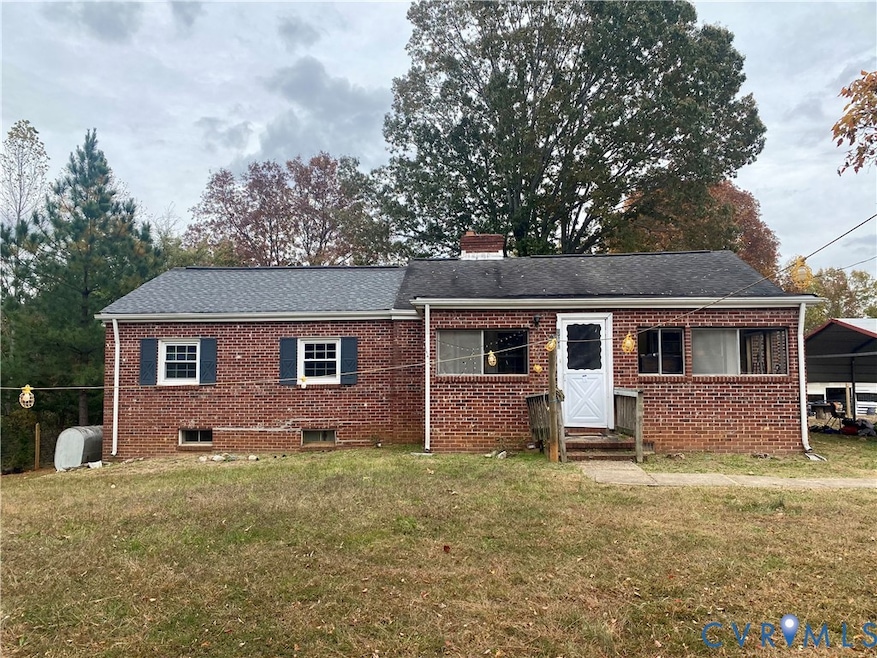 Ranch-style home featuring a front yard, brick siding, heating fuel, a chimney, and roof with shingles