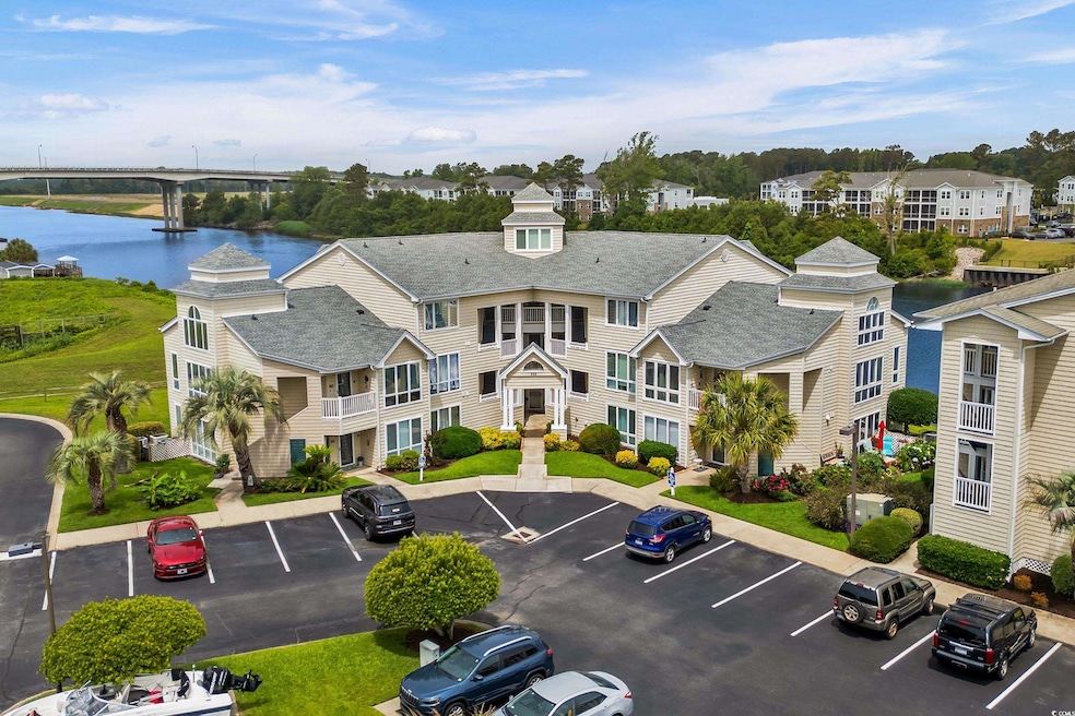 View of property with uncovered parking and a water view