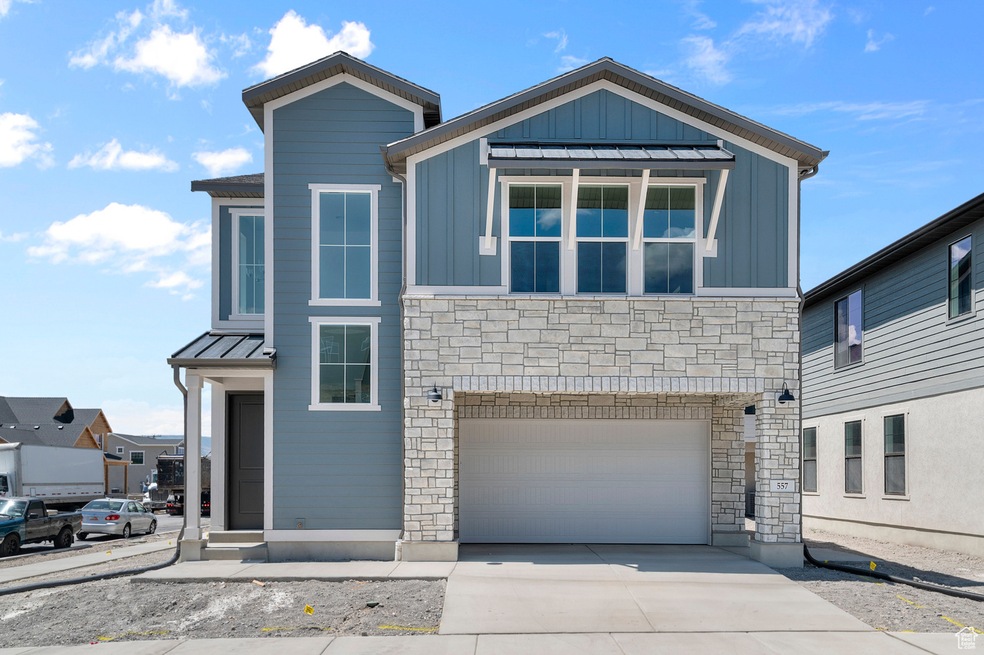View of front of home featuring stone siding, an attached garage, driveway, and board and batten siding
