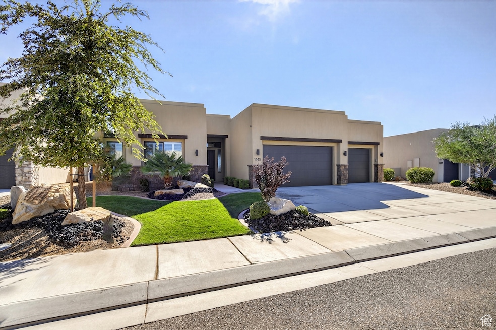 Adobe home featuring driveway, a front yard, a garage, stucco siding, and stone siding
