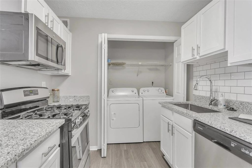 Kitchen with washing machine and dryer, white cabi
