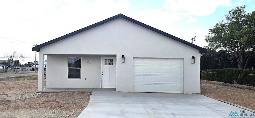 View of front of home with stucco siding, driveway, covered porch, and a garage