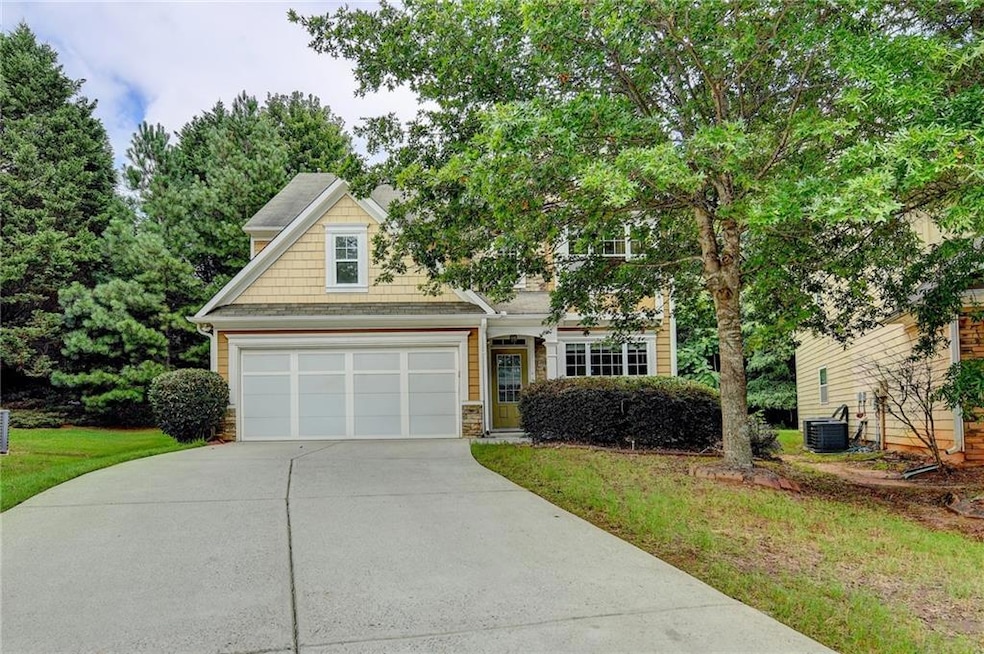 View of front of home with driveway, stone siding, a front yard, and roof with shingles