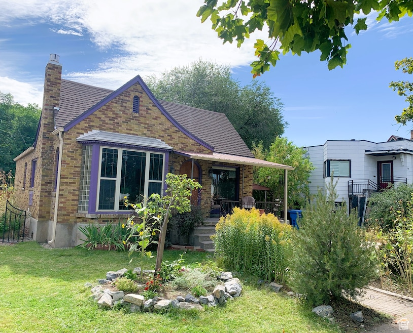 View of front of house featuring brick siding, a chimney, and a front lawn