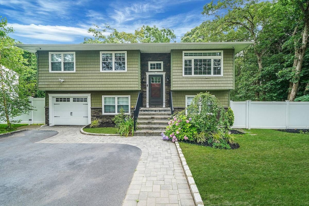 Bi-level home featuring a garage, stone siding, and driveway