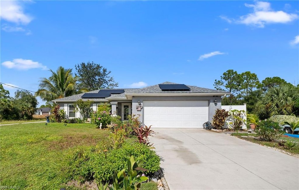 Ranch-style house with roof mounted solar panels, concrete driveway, an attached garage, a front yard, and stucco siding