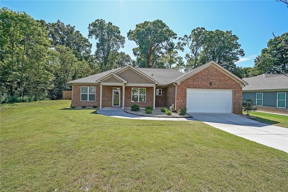 View of front of property featuring a garage, brick siding, concrete driveway, and a front lawn