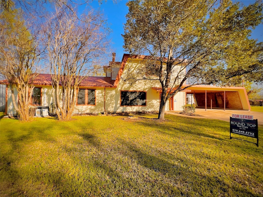 Back of house featuring a lawn and a carport