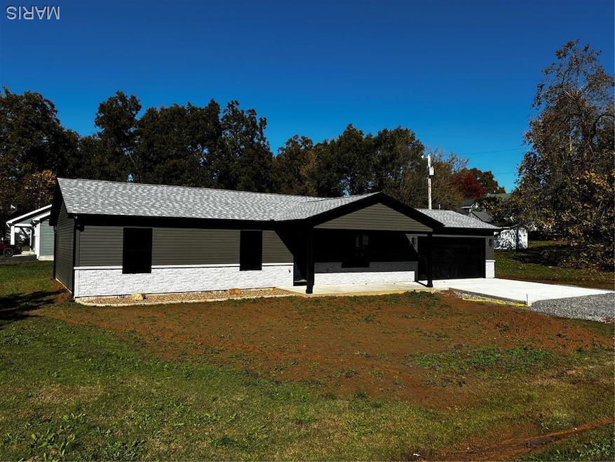 Ranch-style house featuring a garage, a front yard, driveway, a porch, and stone siding
