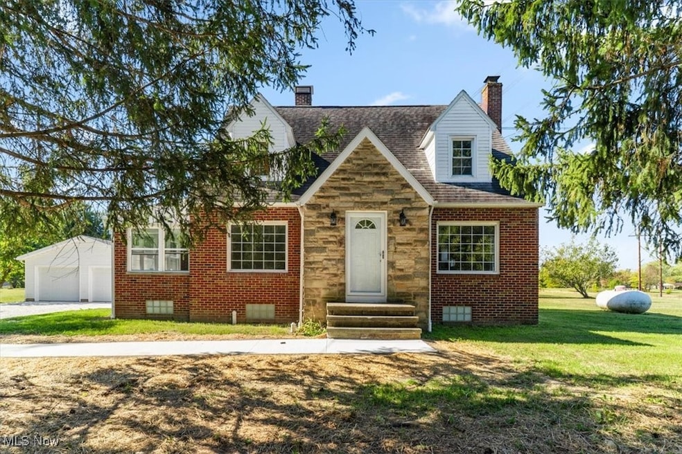 View of front of property featuring a chimney, stone siding, roof with shingles, a front lawn, and brick siding