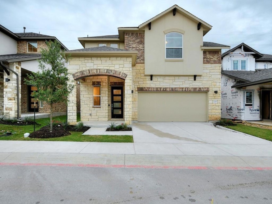 View of front facade with stone siding, driveway,
