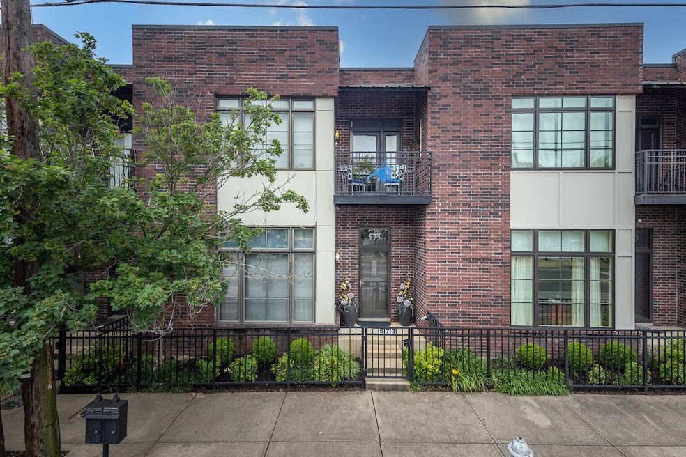 View of front of home featuring a fenced front yard, brick siding, and a balcony