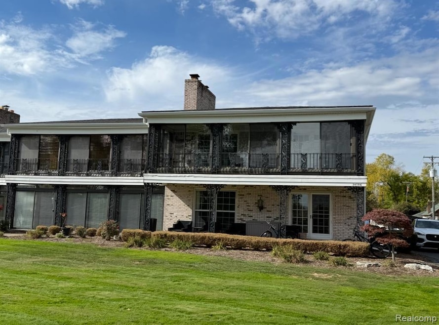 Rear view of property with a chimney, a balcony, brick siding, and a patio area