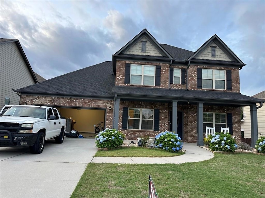 Craftsman-style house featuring brick siding, driveway, an attached garage, and a front lawn