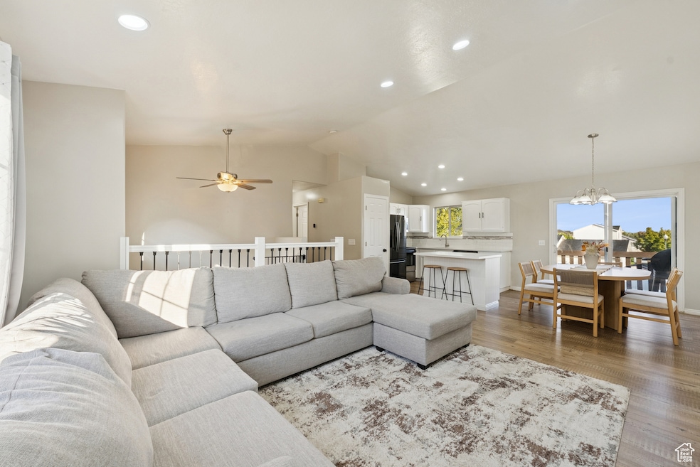 Living area with recessed lighting, lofted ceiling, wood finished floors, a chandelier, and a ceiling fan