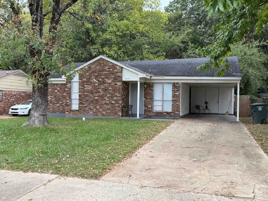 Ranch-style home with brick siding, a front lawn, concrete driveway, an attached carport, and a shingled roof