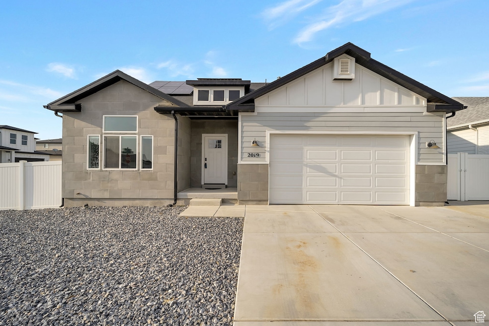 View of front of property with driveway, solar panels, a garage, and board and batten siding