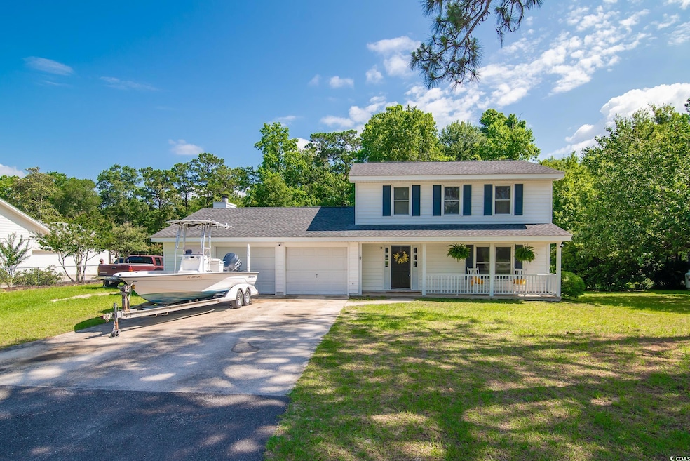 Traditional-style home with covered porch, asphalt driveway, an attached garage, and a front yard