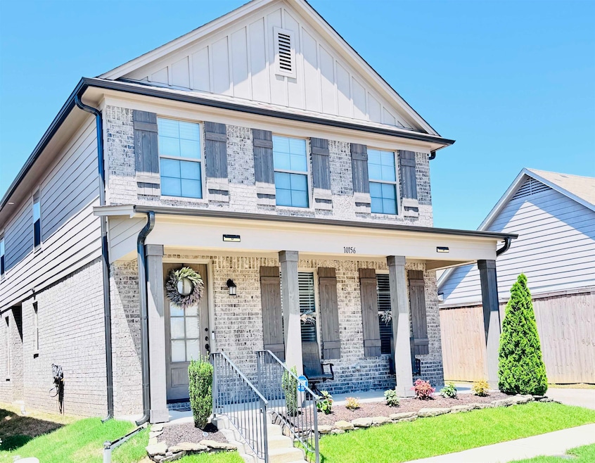 View of front of property featuring brick siding, a porch, and board and batten siding