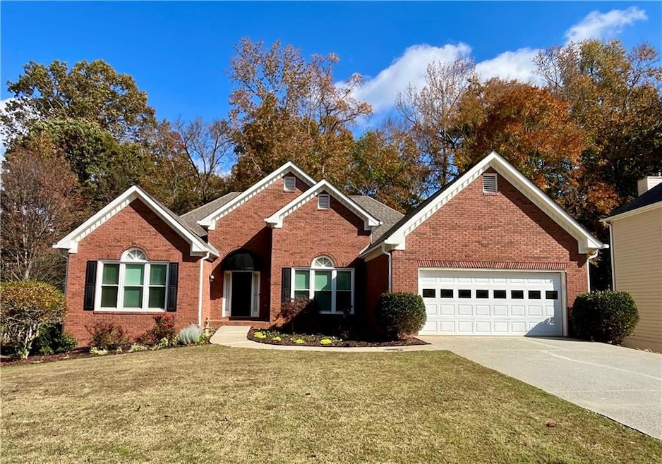 Ranch-style home featuring a front lawn, concrete driveway, brick siding, and a garage