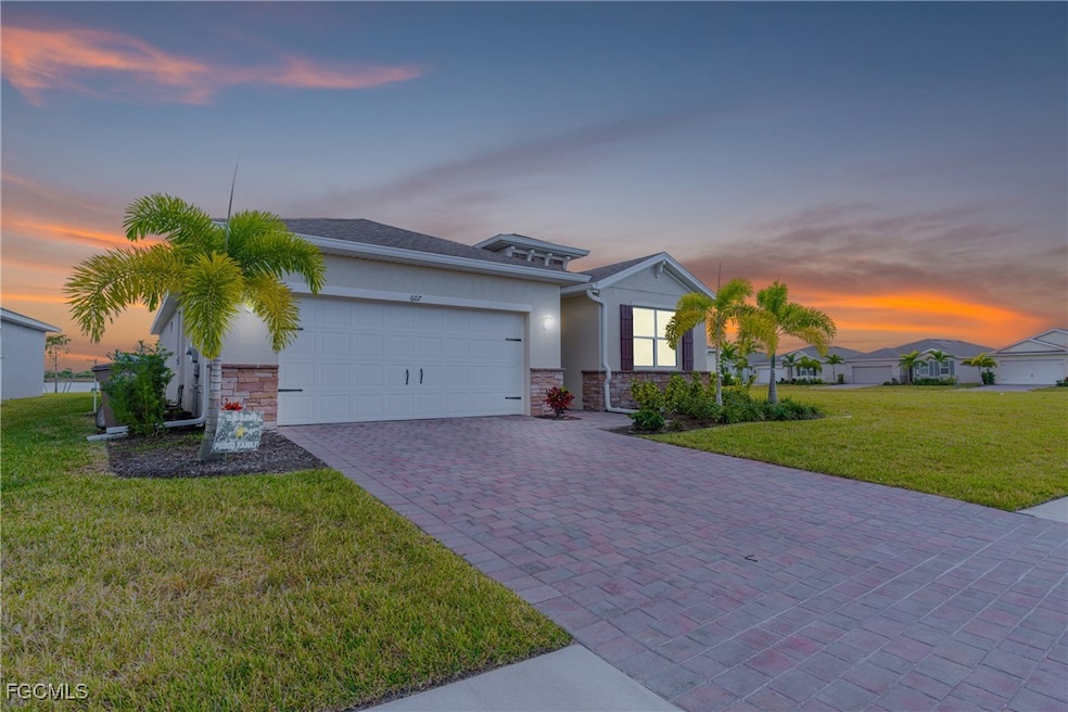 View of front facade featuring stone siding, a front lawn, stucco siding, and decorative driveway