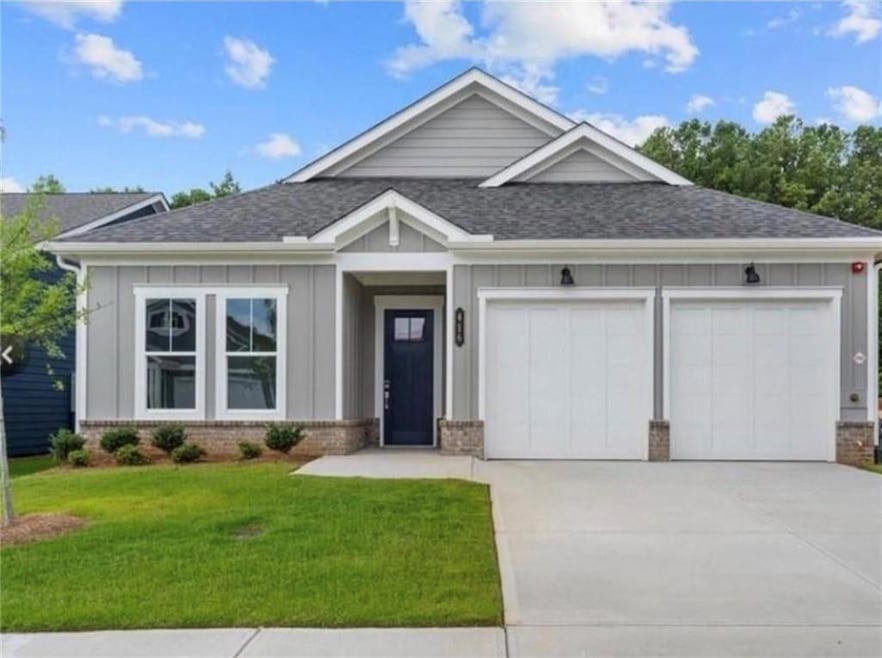 View of front facade featuring brick siding, a shingled roof, board and batten siding, an attached garage, and driveway