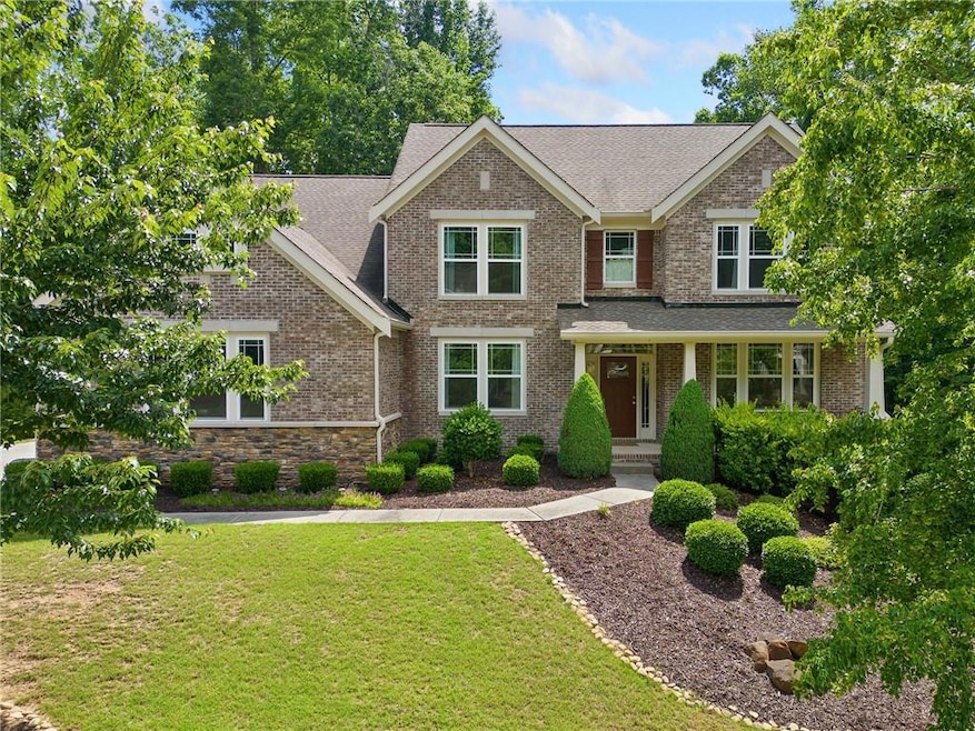 View of front of home with a front yard, brick siding, and roof with shingles