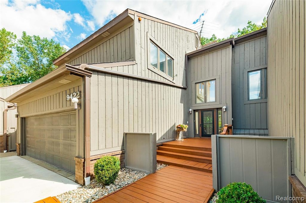 View of side of property featuring a deck, an attached garage, and concrete driveway