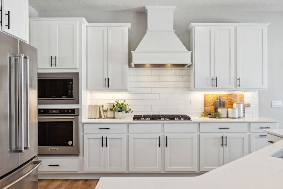 Welcome to the Whitney floor plan and the kitchen of your dreams! Stunning wood hood, gas cooktop, built in wall oven and microwave just to name a few of the gourmet features!  Home for sale will have this exact kitchen and color package.