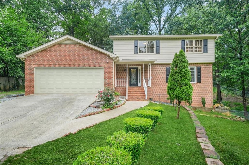 View of front of home featuring a garage, driveway, brick siding, and a front lawn