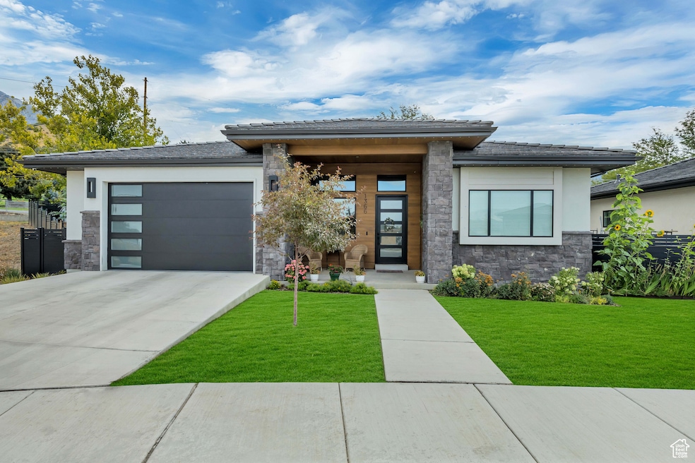 Modern Prairie-style home featuring low maintenance stone and stucco, tile roof, attached garage, and complete landcaping