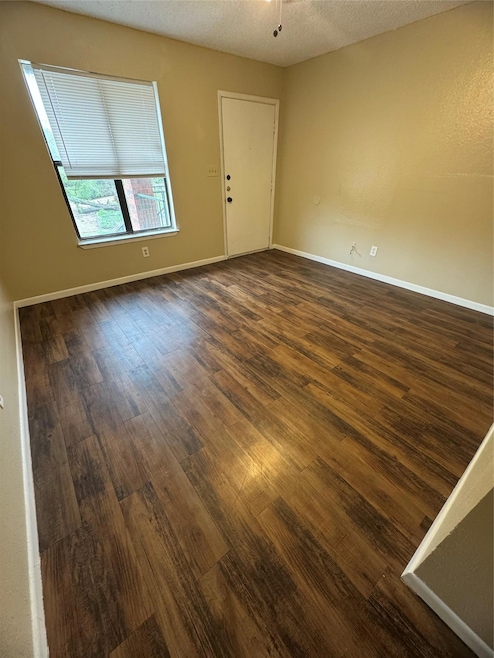 Empty room with dark wood-type flooring, a textur