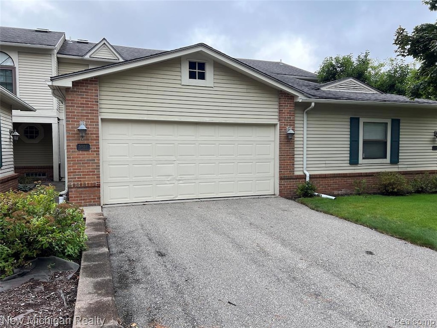 View of front of home with brick siding, asphalt driveway, and a shingled roof